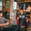 Two men enjoying a relaxed conversation with laptops in a cozy Brazilian café.